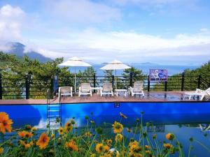 a patio with chairs and umbrellas next to a pool at goheung suwan pension in Goheung