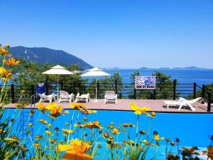 a swimming pool with chairs and umbrellas and flowers at goheung suwan pension in Goheung
