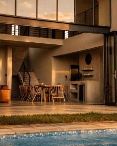 an open living room with a table and a swimming pool at Sanyati Villa in Mmukubyane