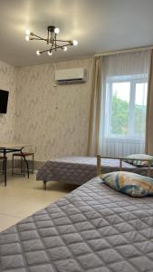 a bedroom with two beds and a table and a window at Эталон АПАРТ-ОТЕЛЬ Aqtobе in Aktobe