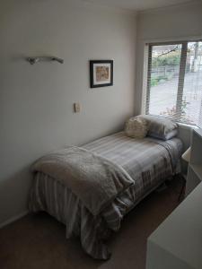a bed in a bedroom with a large window at Modern Home in Central Location in New Plymouth