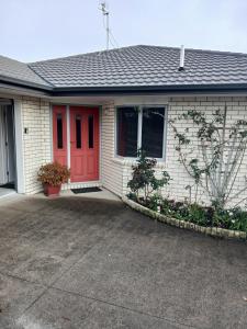 a house with a red door and a driveway at Modern Home in Central Location in New Plymouth