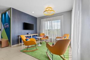 a waiting room with chairs and a table and a tv at Spark by Hilton Terrell in Terrell