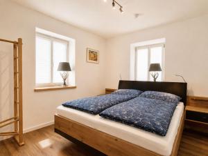 a bedroom with a bed and two windows at Guade Stub'n Franzi in Huglfing