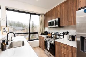 a kitchen with wooden cabinets and a large window at Modern condo with town and mountain views in Evergreen