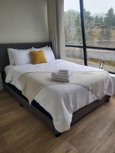 a bed with towels on it in a room with a window at Modern condo with town and mountain views in Evergreen
