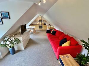 a living room with a red couch in a attic at Hydrangea Cottage in St Austell