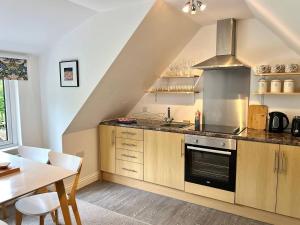 a kitchen with wooden cabinets and a sink and a table at Hydrangea Cottage in St Austell