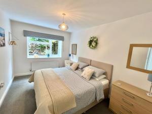 a bedroom with a bed and a window at Hydrangea Cottage in St Austell