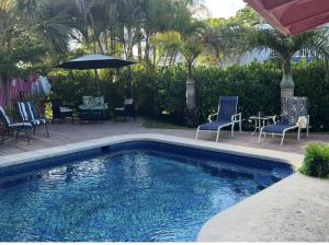 a swimming pool with chairs and a table and an umbrella at Coastal Bungalows--The Flamingo Bungalow in Fort Lauderdale