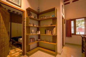 a room with shelves with books and a bed at Golden Loom Homestay in Kanchipuram +7 photos