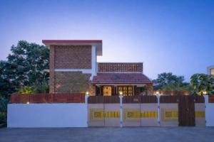 a house with a white fence in front of it at Golden Loom Homestay in Kanchipuram