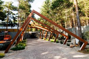 a wooden bridge over a walkway in a park at Altay Resort in Shchūchīnsk
