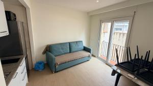 a blue couch in a living room with a window at Apartamentos Lin in Lloret de Mar