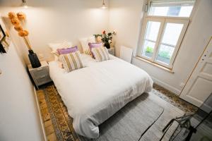 a bedroom with a white bed with pillows and a window at Maison Lumière Arras in Arras