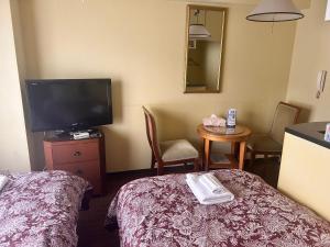 a hotel room with a tv and a bed and a table at Nikko Park Lodge Tobu Station in Nikko