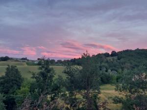 a sunset over a green field with trees at Orchard House South Room in Pergola