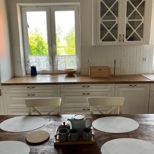 a kitchen with white cabinets and a table and chairs at Dom Nowe Krzywe in Nowe Krzywe