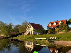 a house next to a river with a boat on it at Dom Nowe Krzywe in Nowe Krzywe