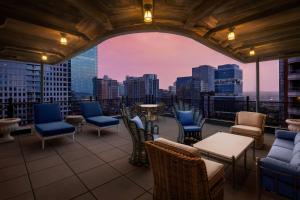 a rooftop patio with chairs and tables and a view of the city at The Stoneleigh, Autograph Collection in Dallas