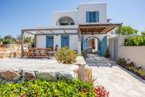 a white house with a patio with a table and chairs at Alma Libre Villas in Kastraki