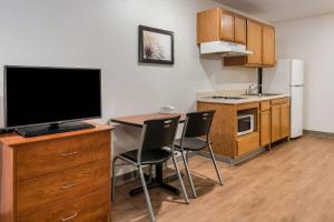 a kitchen with a desk with a television and chairs at WoodSpring Suites Abilene in Abilene