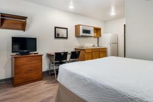 a bedroom with a bed and a kitchen with a tv at WoodSpring Suites Abilene in Abilene