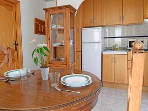 a kitchen with a wooden table and a white refrigerator at Apartamentos Costa Azahar 3000 in Alcossebre