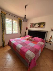 a bedroom with a bed with a pink and gray quilt at Villa Aghjanella in Patrimonio