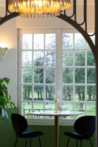 a dining room with a table and chairs and a large window at Quatorze - manoir au coeur du parc du Château de La Garnache in La Garnache