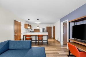 a living room with a blue couch and a kitchen at Everhome Suites Stockbridge Atlanta in Stockbridge