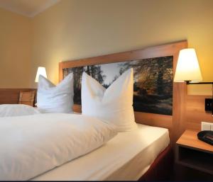 ein Hotelzimmer mit einem Bett mit weißen Kissen in der Unterkunft Hotel Zum Kellermann in Grafenau