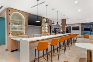 a cafeteria with orange chairs and a long counter at Cambria Hotel Euless - DFW Airport South in Euless