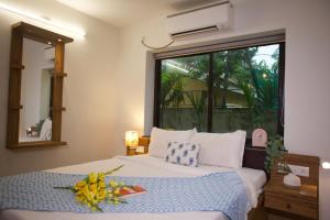 a bedroom with a bed with a window and a flower arrangement on it at 4BHK Villa in Anjuna with Jacuzzi & Pool in Anjuna +45 photos
