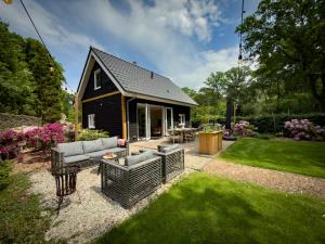 a small black house with a patio and grass at Heemhoeve Lodge in Emst