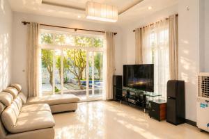 a living room with a couch and a flat screen tv at Kegotel Luxury Villa - Bãi Tắm Long Cung in Vung Tau