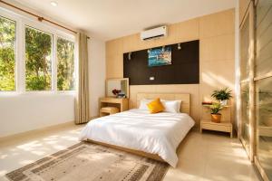 a bedroom with a bed and a tv on the wall at Kegotel Luxury Villa - Bãi Tắm Long Cung in Vung Tau +33 photos