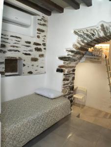 a bedroom with a bed and a stone wall at Μαγαζάκι in Tripótamos