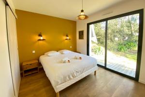 a bedroom with a white bed with a large window at Villa des Dunes Beach 600m Private Jacuzzi Pine Forest Nature Sleeps 8 in Brem-sur-Mer