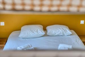a bed with two white pillows and a yellow wall at Villa des Dunes Beach 600m Private Jacuzzi Pine Forest Nature Sleeps 8 in Brem-sur-Mer +41 photos