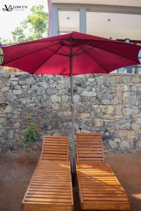 two benches with a red umbrella next to a stone wall at Velowyn Ella in Ella