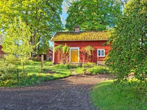 a red house with a yellow door next to a road at Stastugan in Grönhult +4 photos