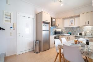 a kitchen with a table with chairs and a refrigerator at Phoebes Place At Kalamaki Court, 2 Bedroom Villa With A Shared Pool - Fully Refurbished For 2026 in Kalamaki +21 photos