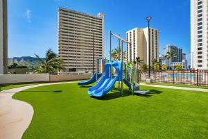 a playground in a park with green grass and buildings at Aston at the Waikiki Banyan in Honolulu