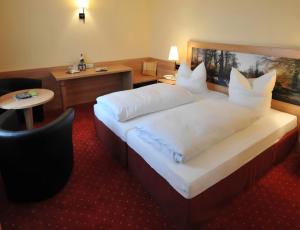 ein Hotelzimmer mit einem großen Bett und weißen Kissen in der Unterkunft Hotel Zum Kellermann in Grafenau