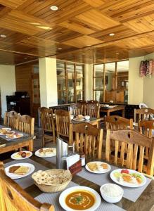 a dining room with tables and chairs with plates of food at Bliss of Heaven in Jagatsukh