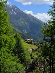 a view of a mountain with a church in the distance at Hotel Foppoli in Poschiavo +47 photos