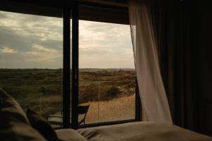 a bedroom with a window looking out at a field at Elements Terschelling by Dutchen in Midsland