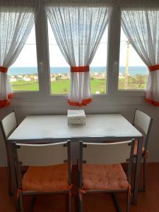 a table and chairs in a room with windows at Chalet unifamiliar Foz-Nois in Barrosa