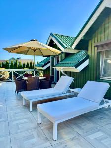 a row of lounge chairs and an umbrella on a patio at Sodyba prie jūros in Palanga